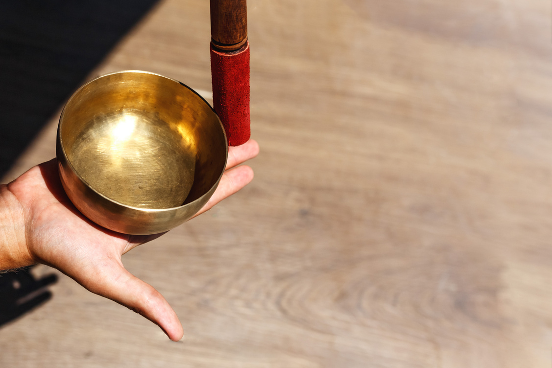 Man hands using singing bowl in sound healing  outdoors, closeup